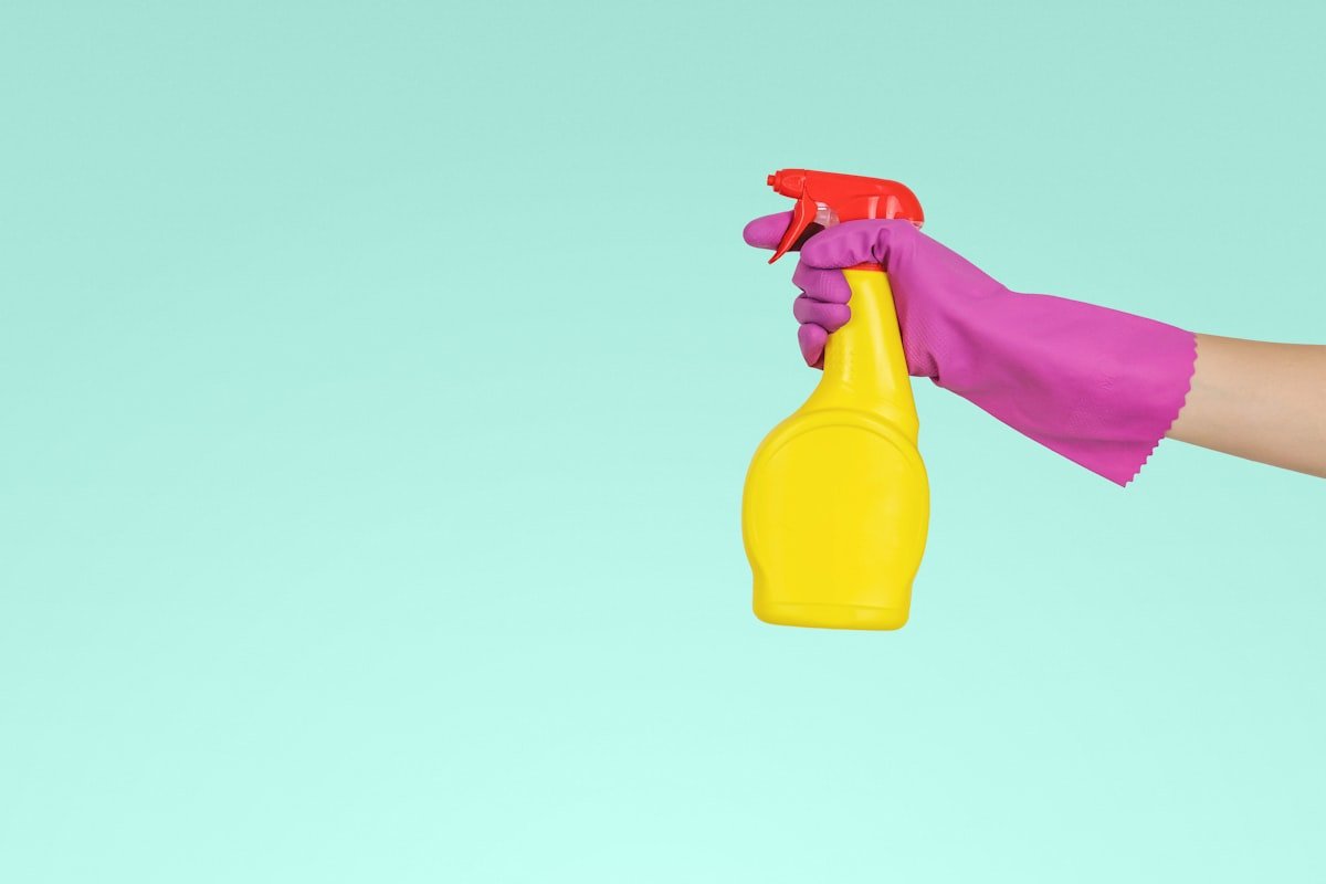Gloved hand holding a spray bottle representing professional cleaning supplies