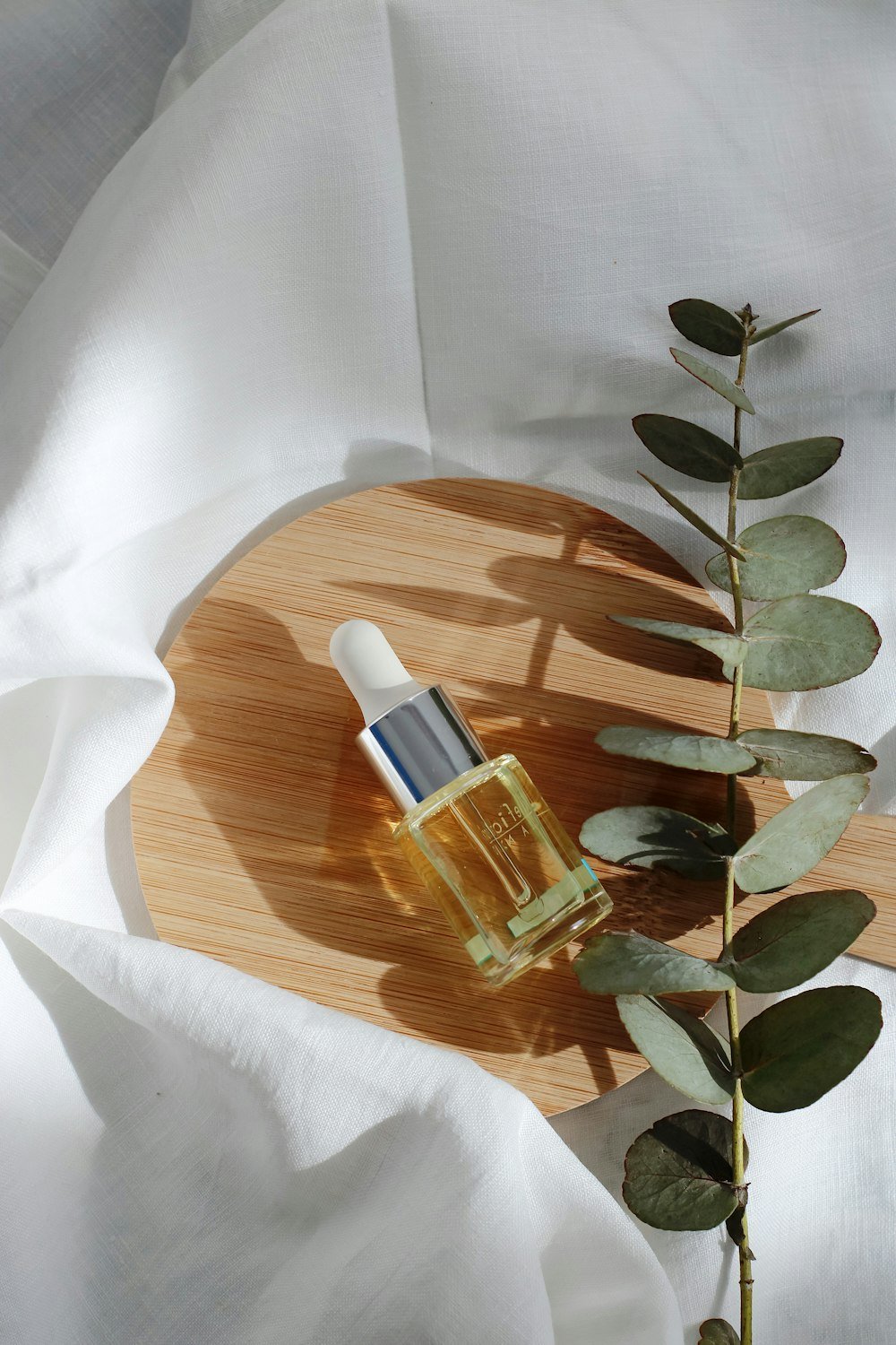 Skincare serum dropper bottle styled on linen and wood